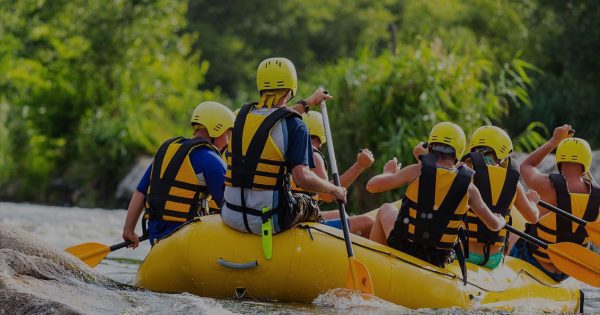 Six adults paddling a raft through the Sturgeon River rapids, the fastest river in Michigan's lower peninsula.