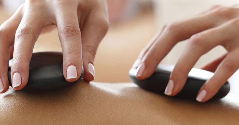 A person receives a hot stone massage at Treetops Spa.