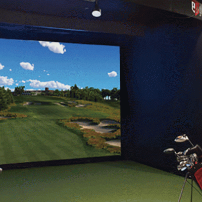 The indoor golf simulator screen at Treetops Resort with bags of golf clubs, ready to play.