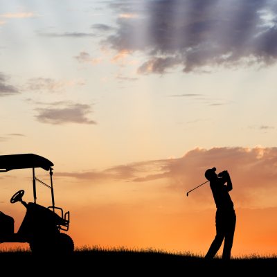Silhouette of golfer with golf cart