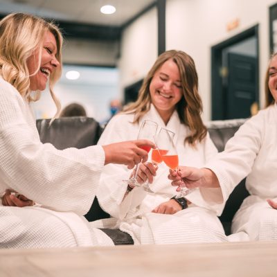 Three women smiling and toasting in spa