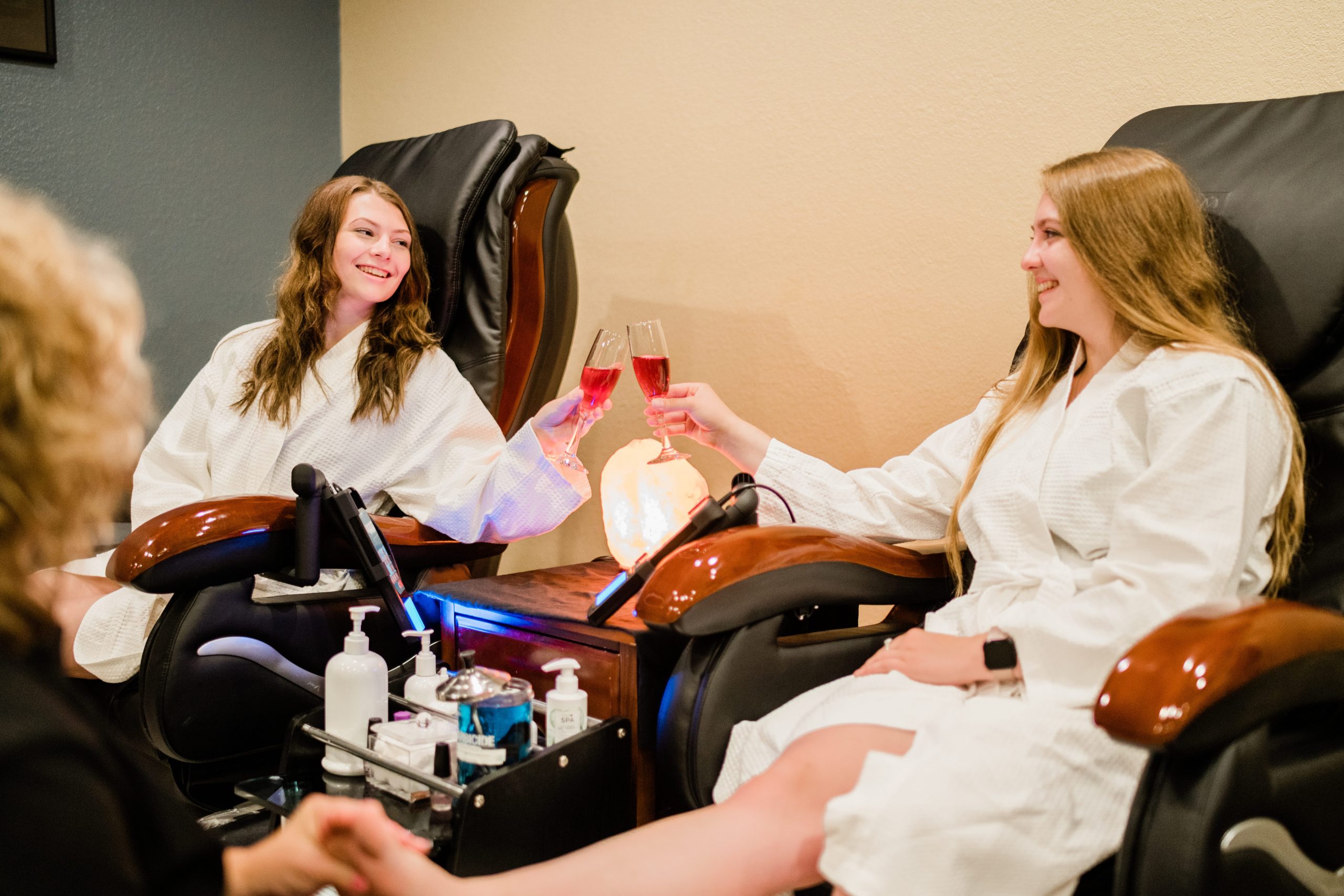 Two young women toasting a mimosa while enjoying spa pedicure