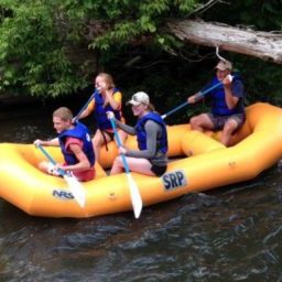 Four people enjoy a rafting trip on a Michigan river.