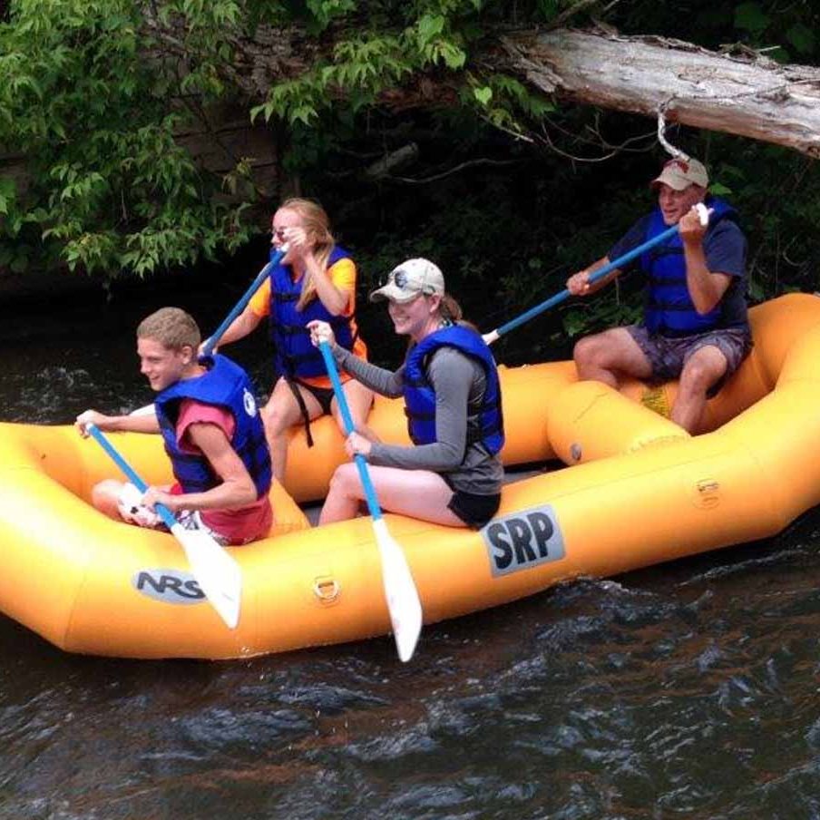 Four people enjoy a rafting trip on a Michigan river while visiting golf resort Michigan Treetops